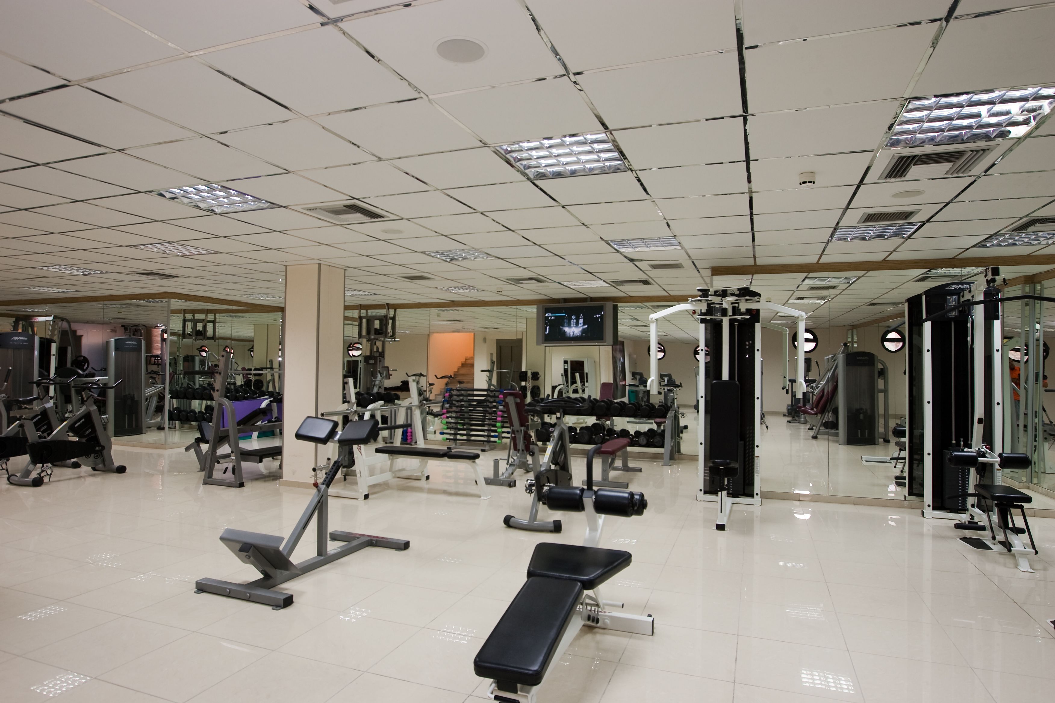 Ett gym med olika typer av träningsutrustning, inklusive löpband, styrketräningsmaskiner och fria vikter.