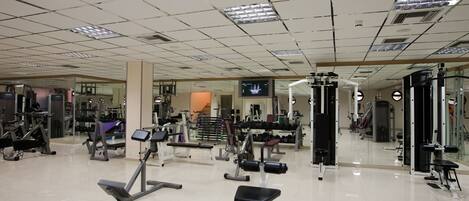 A gym with various exercise equipment, including treadmills, weight machines, and free weights.