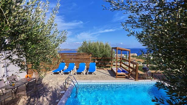 A pool area with blue lounge chairs, a wooden pergola, and a view of the sea. - Elounda Eleon Villas (Agios Nikolaos)