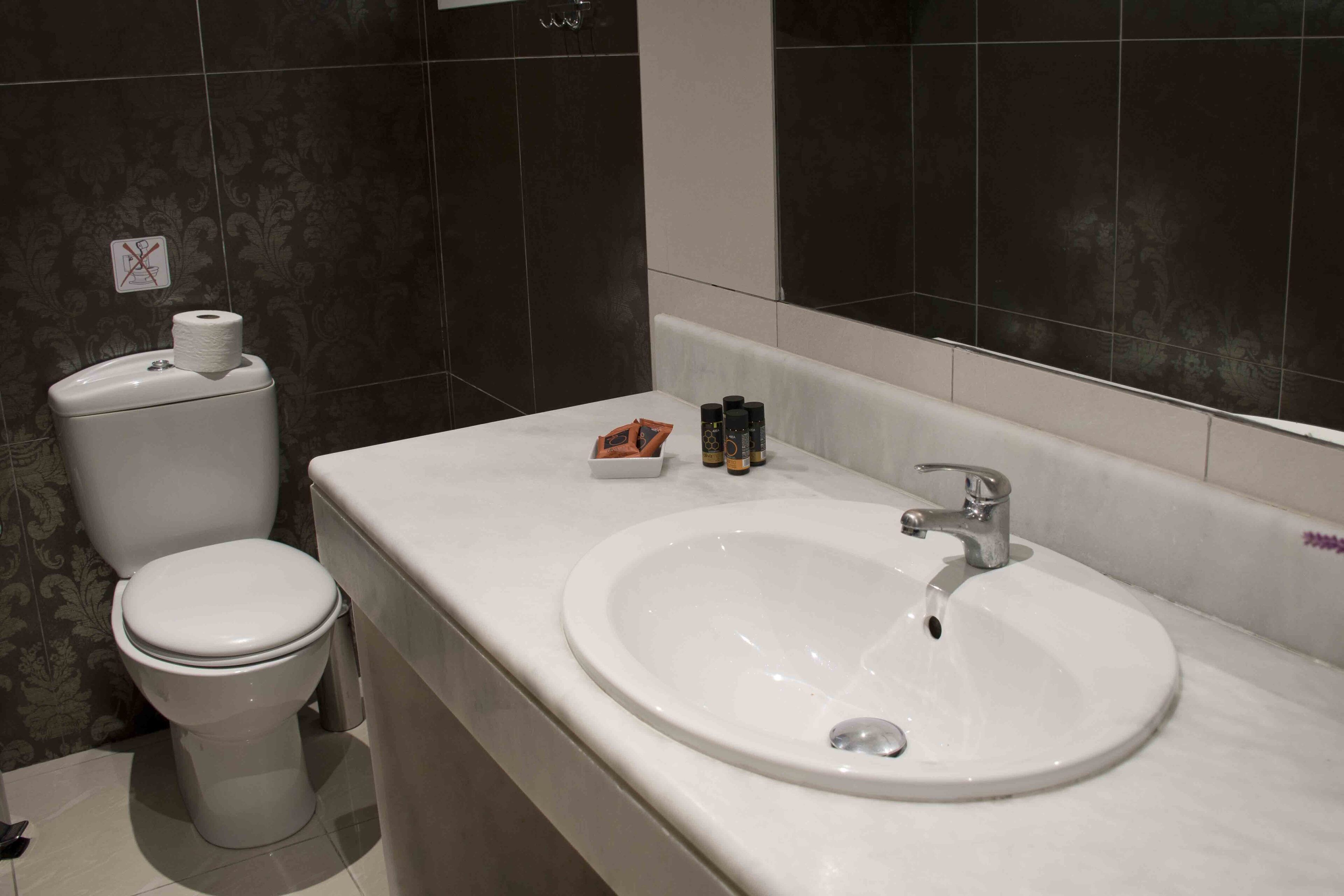 A bathroom with a toilet, a sink, and toiletries on the counter.