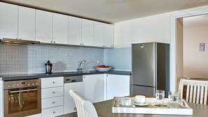 A modern kitchen with white cabinets, a stainless steel refrigerator, a built-in oven, and a tiled backsplash. - Elounda Eleon Villas (Agios Nikolaos)
