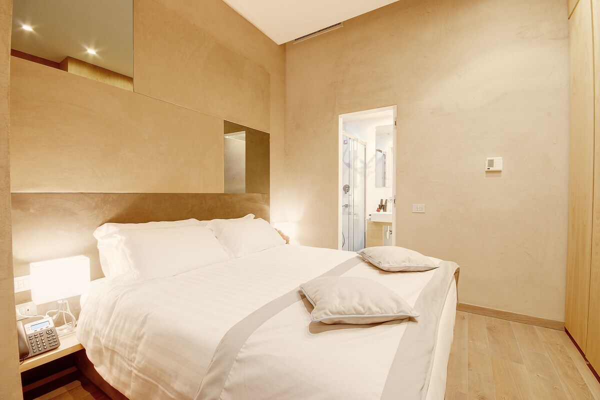 Une chambre d’hôtel moderne avec un grand lit, une table de chevet et un miroir.
