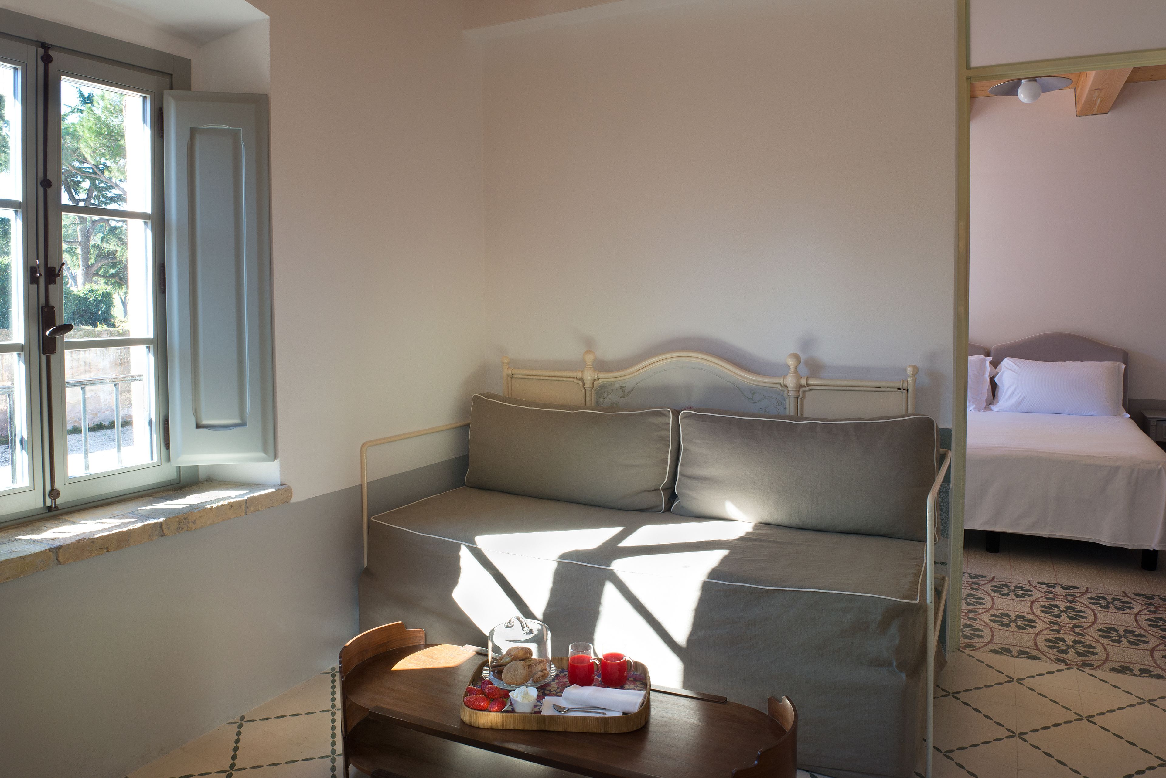 A room with a bed, a window, and a breakfast tray on a table.