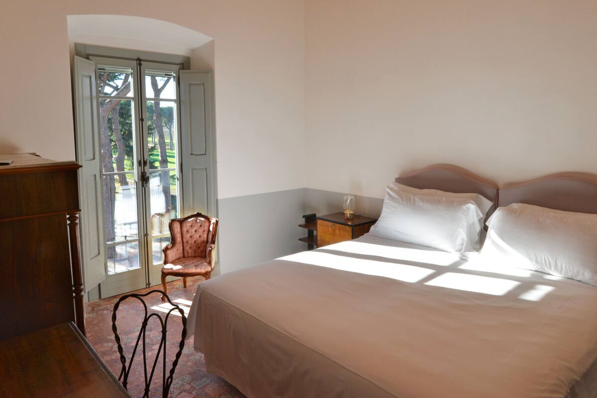 A bedroom with a bed, a chair, a nightstand, and a desk.