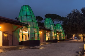 Una hilera de estructuras de vidrio moderno con una luz cálida en su interior, sobre un cielo al anochecer.