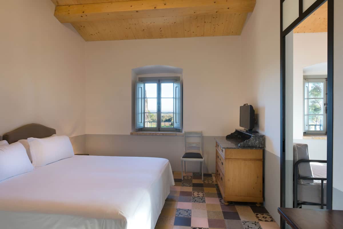 A bedroom with a bed, a dresser, a chair, and a television.