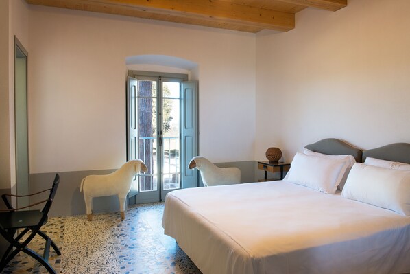 Un dormitorio con una cama grande, una silla y una puerta que da al exterior.