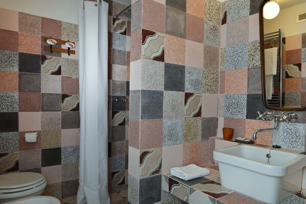 Un baño con ducha azulejada, lavabo e inodoro.