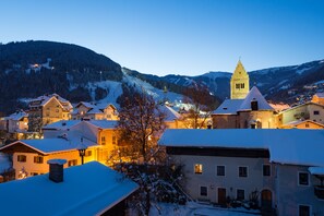 A snow-covered village with traditional architecture, including a prominent church tower, and a mountain backdrop. - Hotel Seehof (Zell am See)