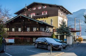 A two-story building with a balcony, a car parked in front, and a mountain in the background. - Hotel Seehof (Zell am See)