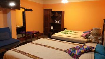 A hotel room with two beds, a sofa, a TV, and a ceiling fan.