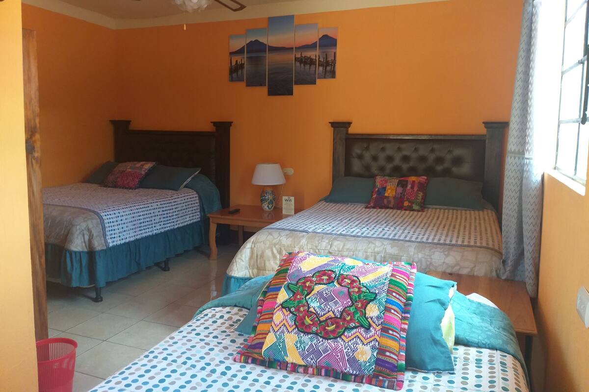 Une chambre d’hôtel avec deux lits, un ventilateur de plafond, une table de chevet et une fenêtre avec des rideaux.