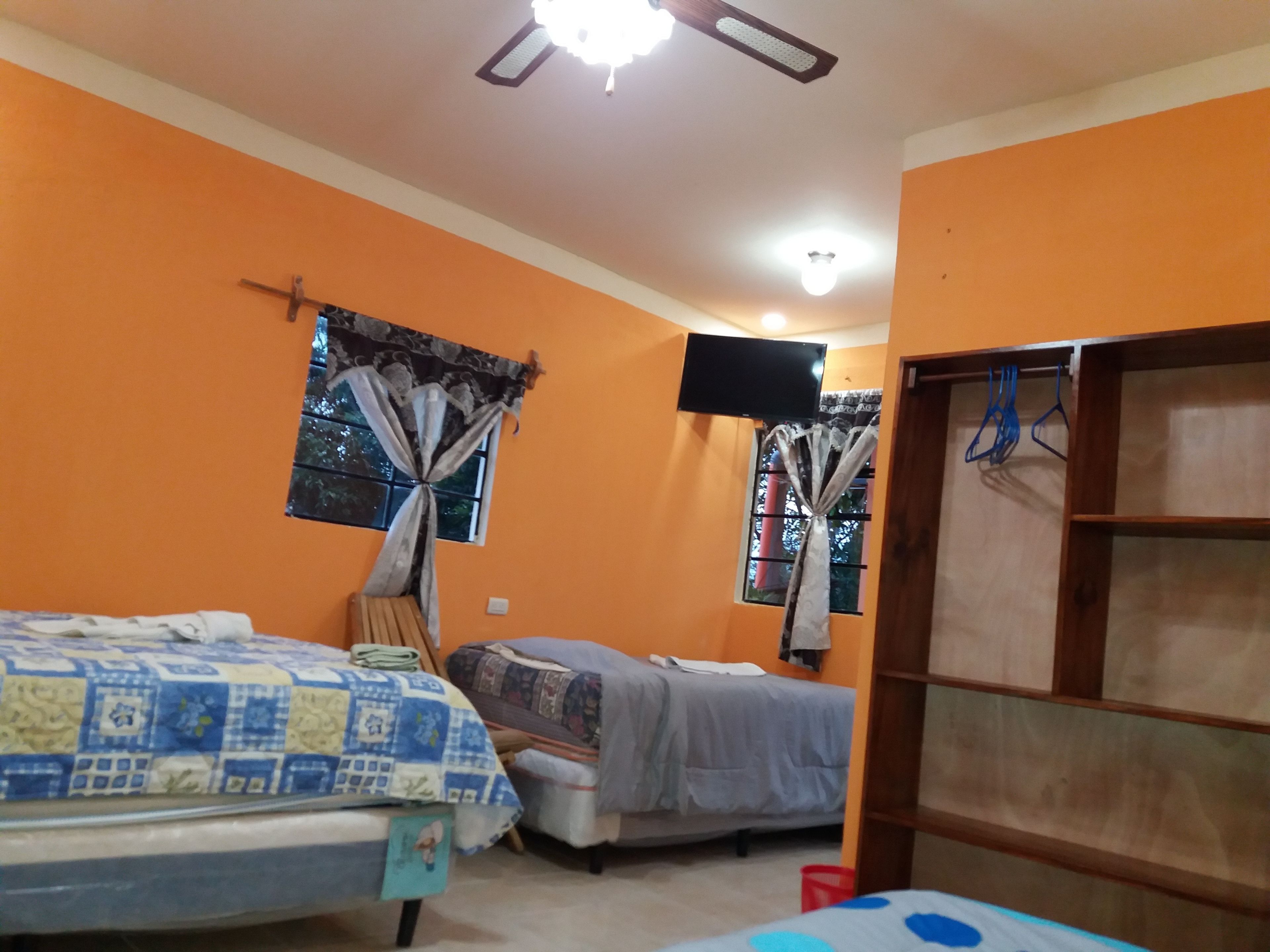 Un dormitorio con dos camas, un televisor y una estantería de madera.