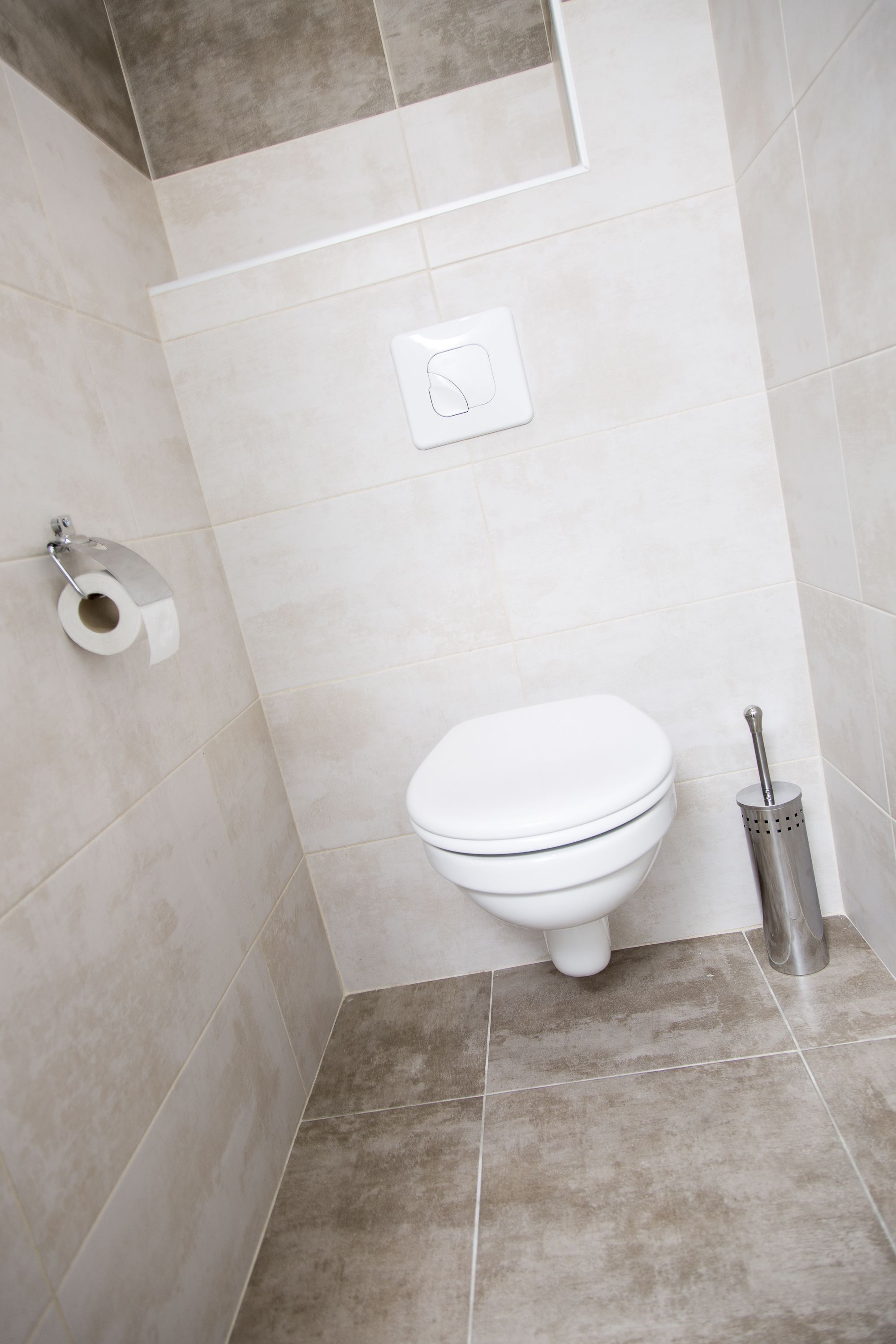 A bathroom with a toilet, a toilet paper holder, and a bidet.