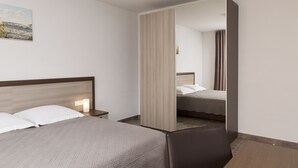 A hotel room with a bed, a nightstand, a mirror, and a painting on the wall.