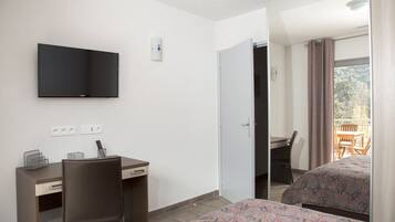 Une chambre d’hôtel comprenant un lit, un bureau avec une chaise, un téléviseur fixé au mur et un balcon avec une table et des chaises.