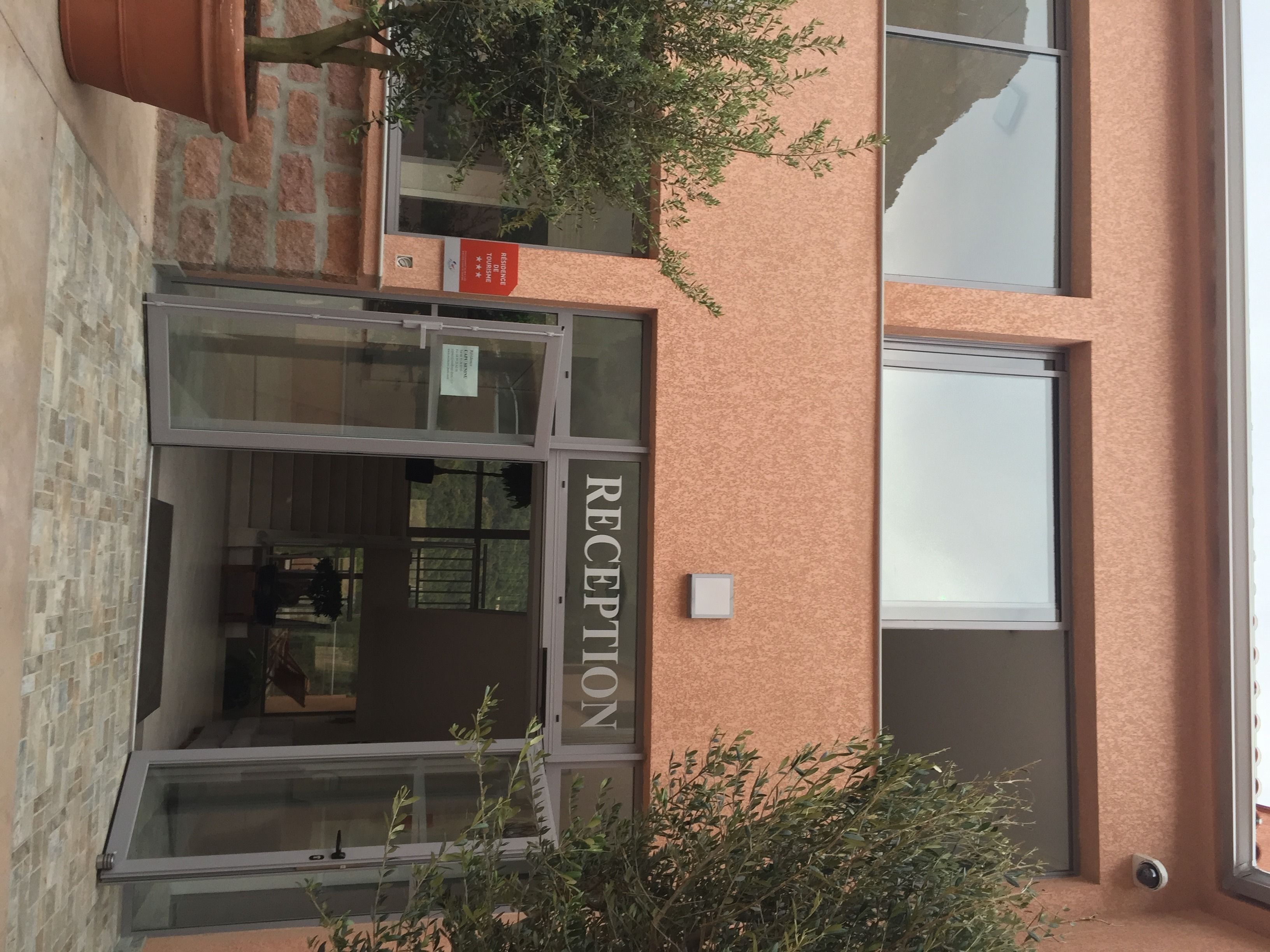 Un espace d’accueil doté d’une porte en verre, d’une enseigne au-dessus et d’une petite fenêtre.
