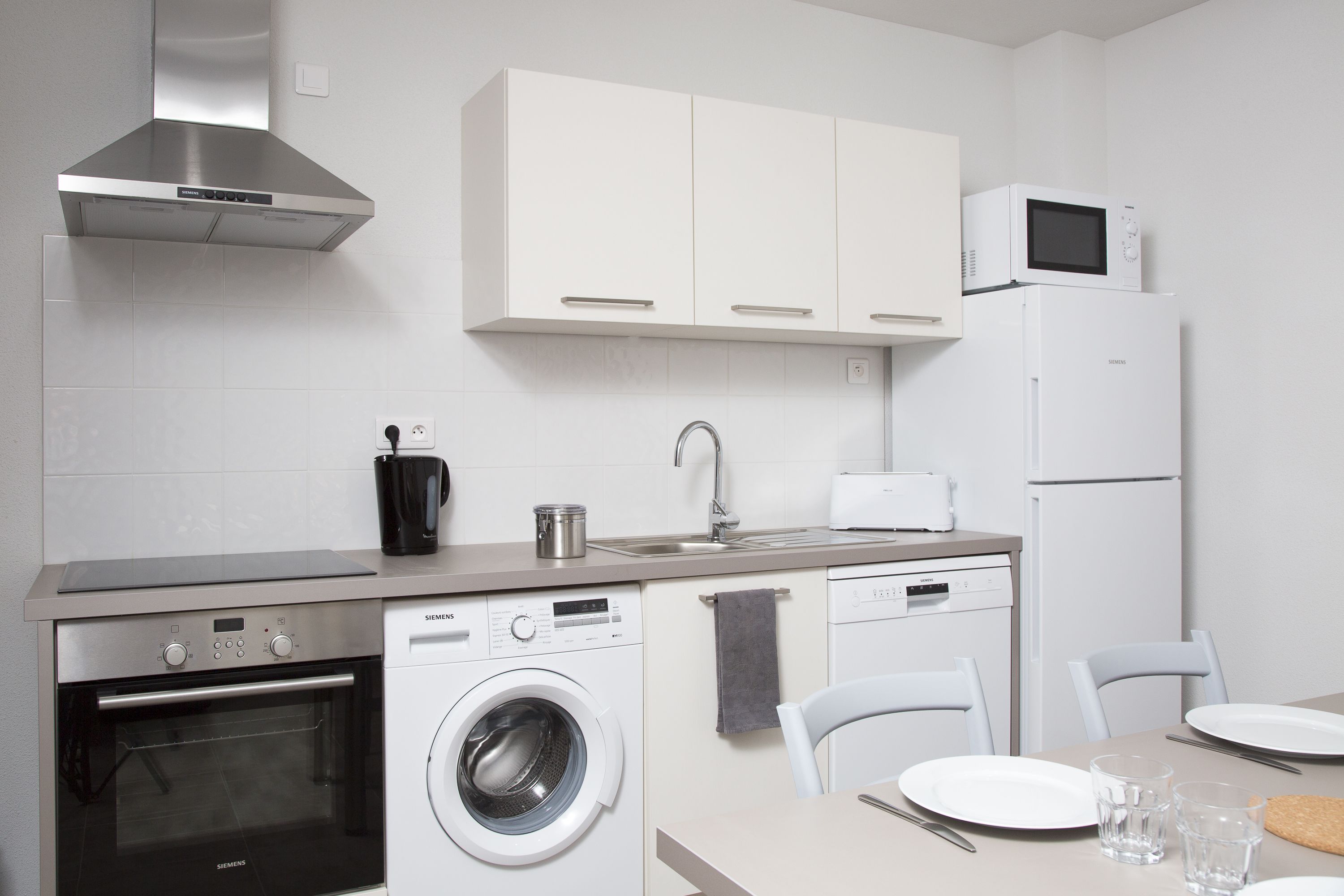 Uma cozinha moderna com eletrodomésticos de aço inoxidável, máquina de lavar louça e micro-ondas.