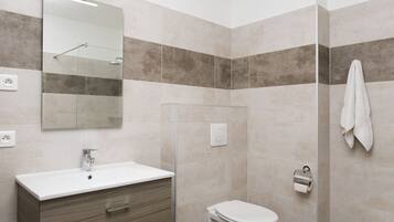 A bathroom with a white sink, a mirror, a toilet, and a towel hanging on the wall.