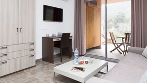 A modern room with a flat-screen TV, a desk with a chair, a sofa, and a balcony with outdoor seating.