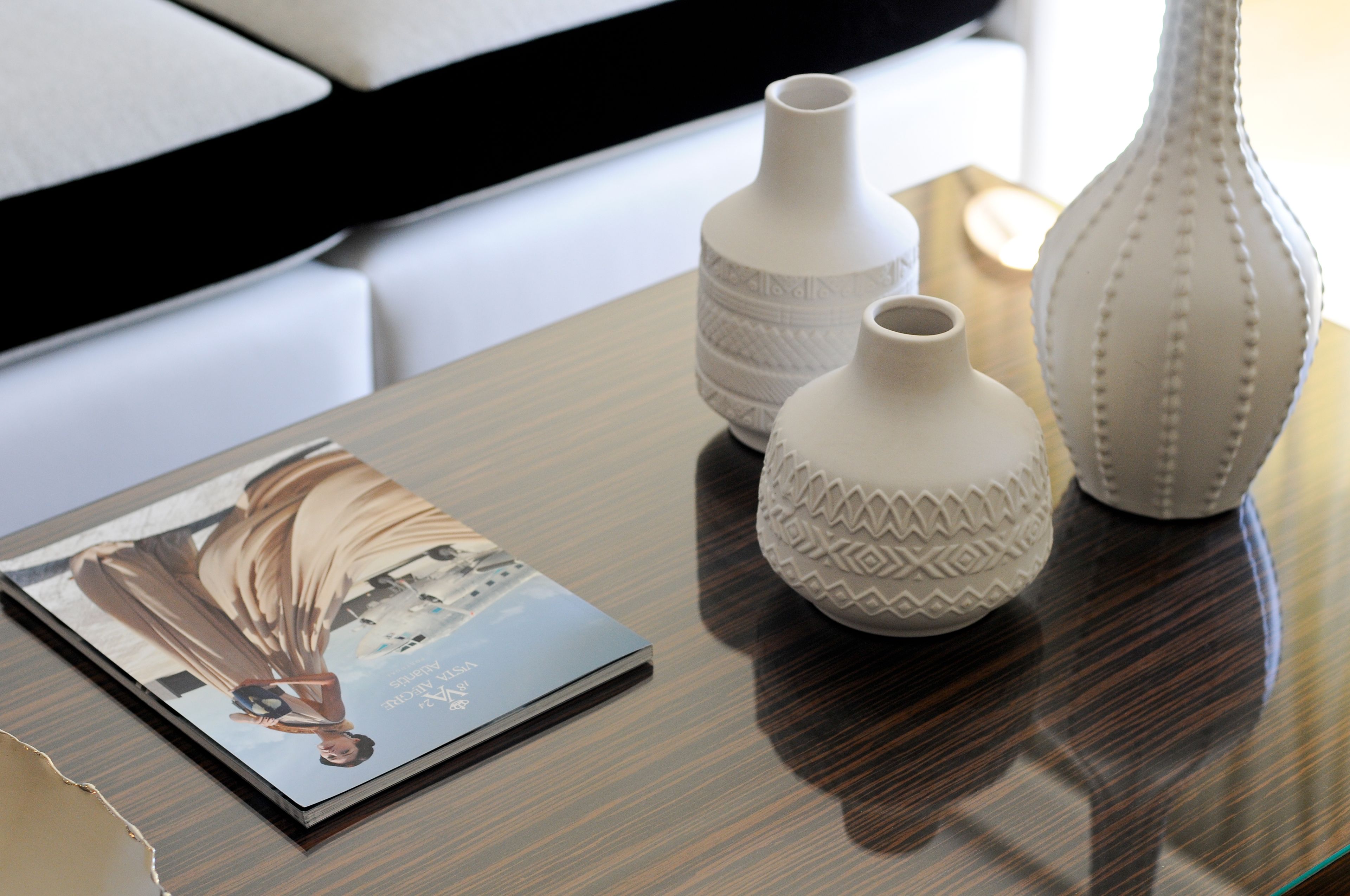 A table with three white vases and a magazine.