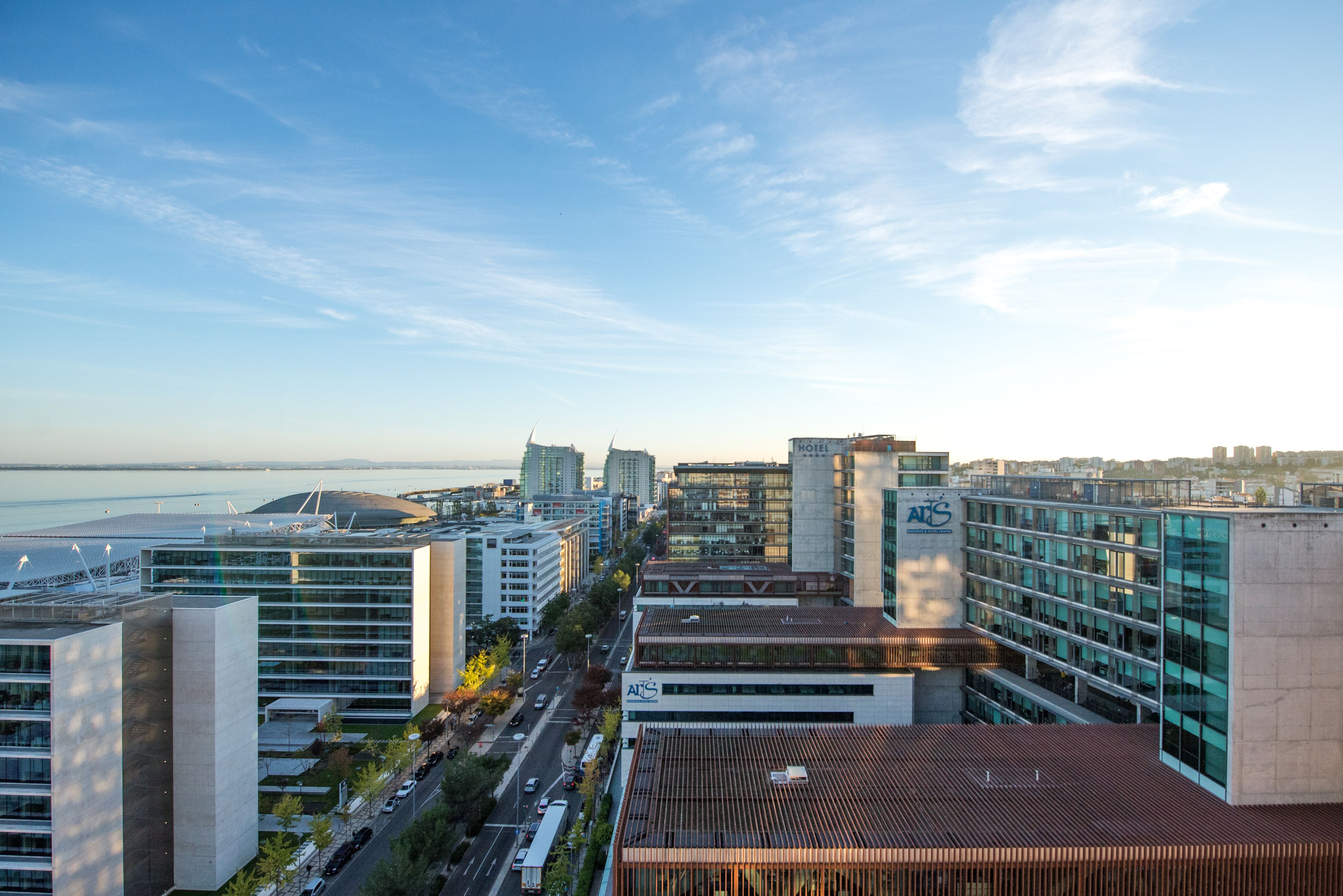 A modern hotel with a prominent 'A' logo, surrounded by other buildings and a clear sky.