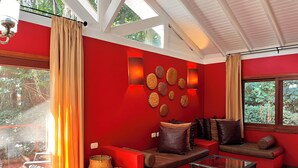 A modern living room with red walls, a glass coffee table, and a sofa with cushions.