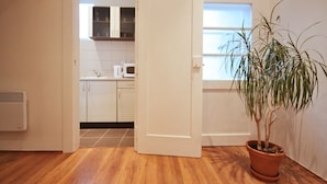 Una cocina con armarios blancos, microondas y una planta en maceta.
