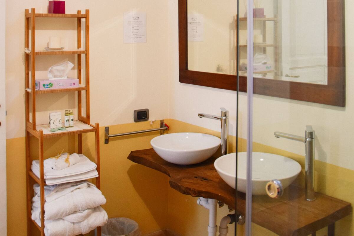 Ein Badezimmer mit einer Holztrennwand, Handtüchern, einem weißen Waschbecken und einem Spiegel.