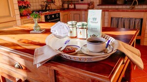 Un plateau de petit-déjeuner avec une tasse de café, un pot de confiture et une bouteille de thé vert, posé sur un comptoir de cuisine en bois.