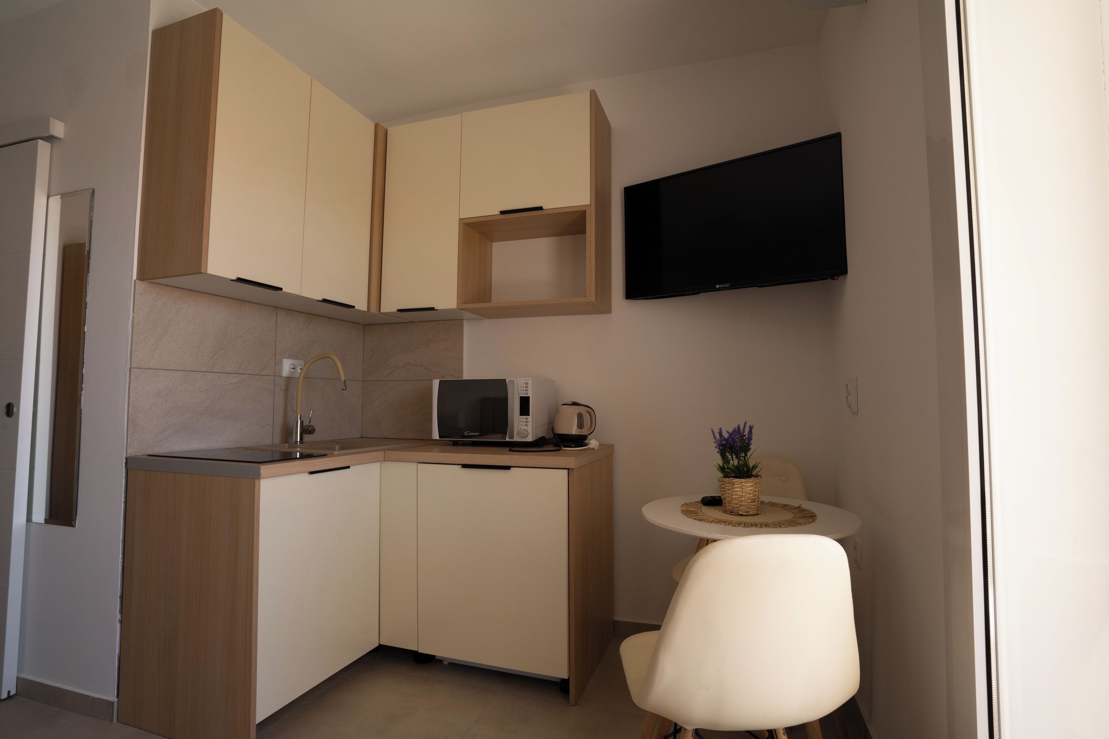 Una cucina compatta con mobili in legno, un forno a microonde e un piccolo tavolo da pranzo con una sedia.