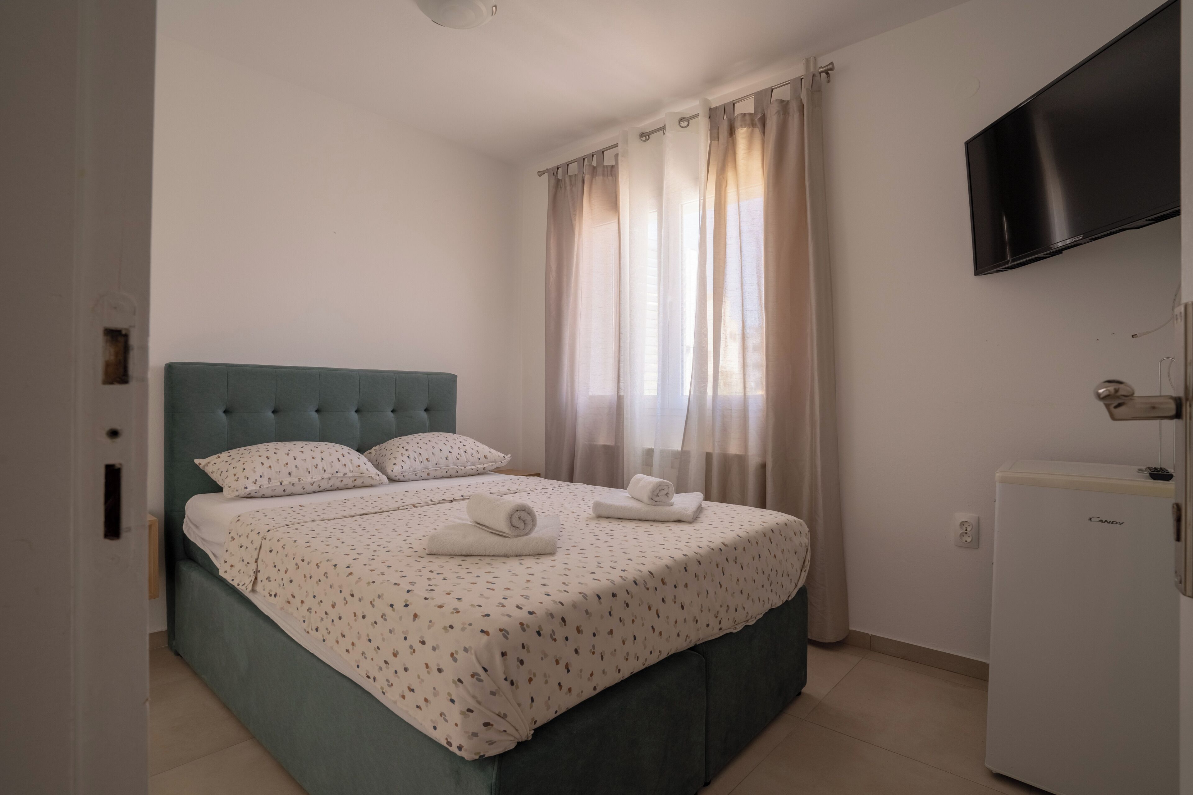 A hotel room with a bed, a television, and a refrigerator.