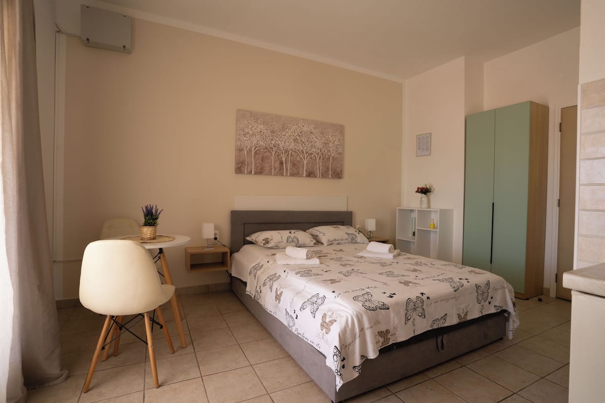A neatly arranged bedroom with a bed, a chair, a small table, and a cabinet.