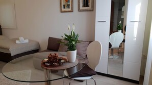 Un soggiorno moderno con un tavolo in vetro, un divano, un tavolino da caffè con una pianta e opere d'arte alle pareti.