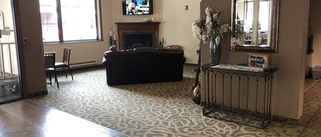 A spacious living room with a fireplace, a television mounted on the wall, and a large window providing natural light.