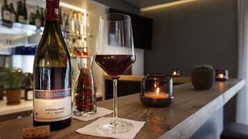 Une bouteille de vin H. Schlumberger et un verre de vin rouge sur le comptoir en bois d’un bar.
