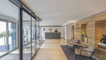 Un área de recepción moderna con mostrador, zona de estar y grandes ventanales.