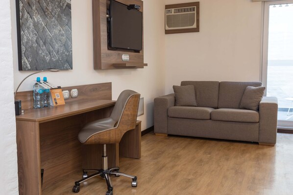 Un espacio de oficina moderno con un escritorio de madera, una silla de cuero y un sofá gris.