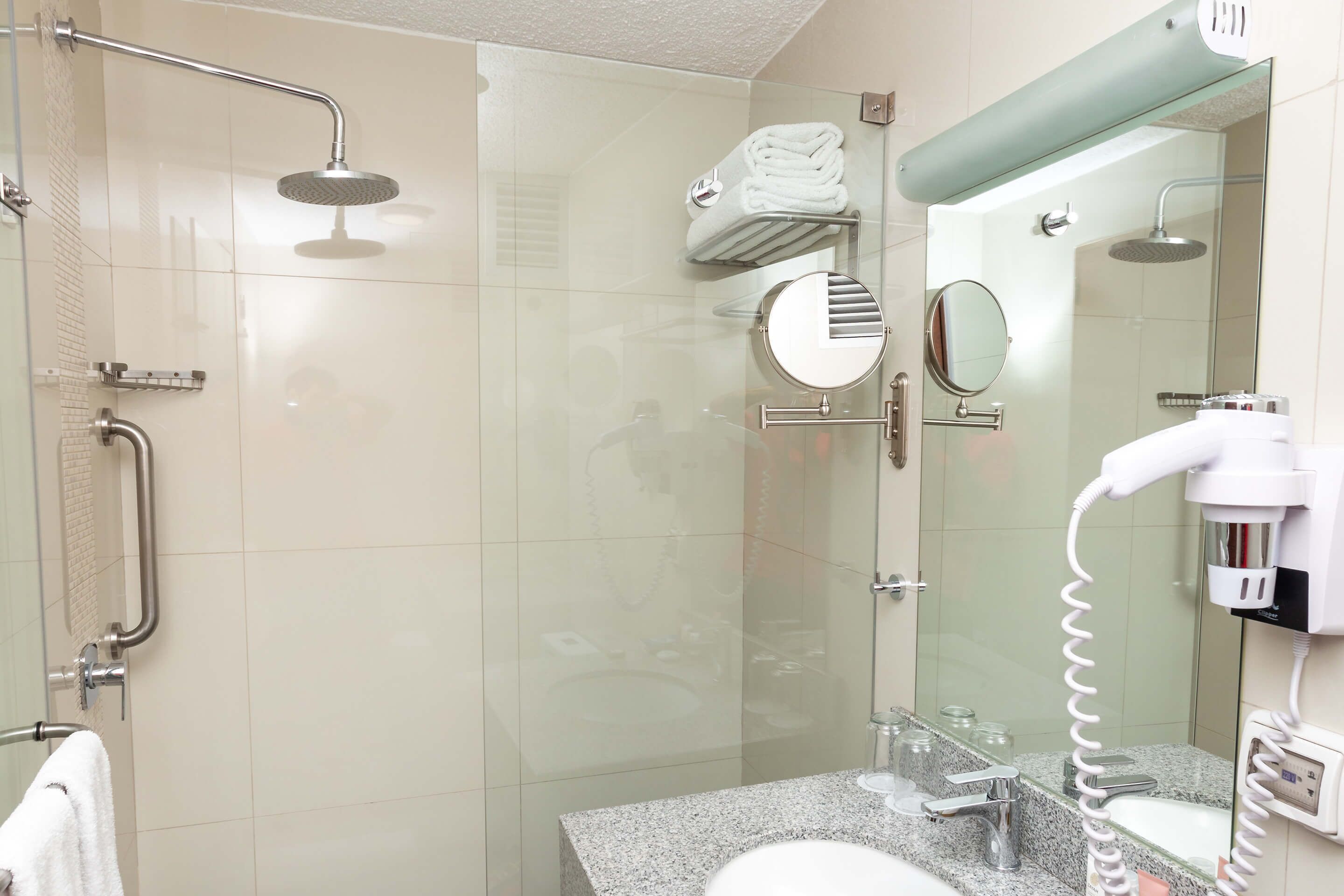 A modern bathroom with a glass shower enclosure, a vanity with a sink, a towel rack, and a hairdryer.