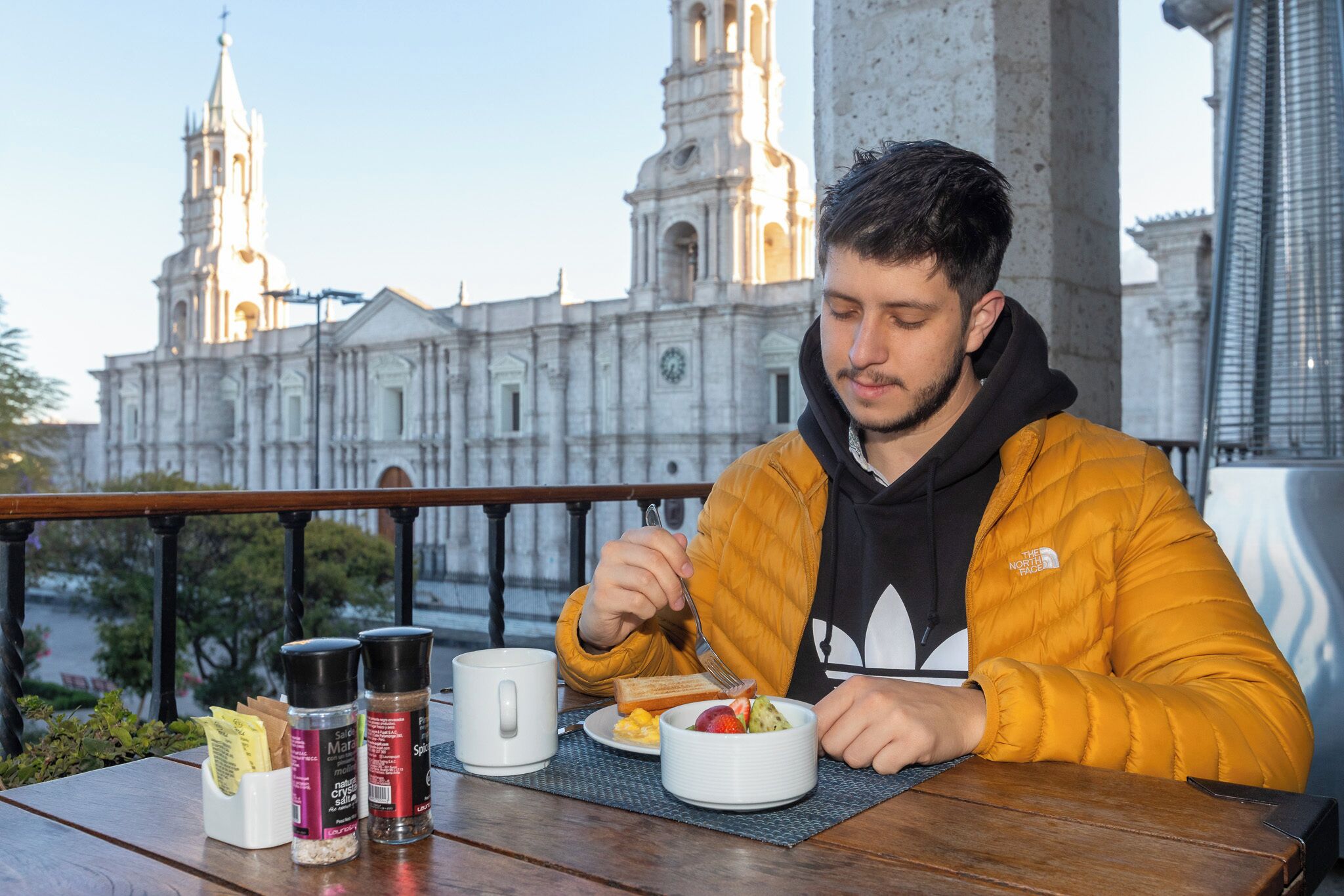 A person dining at a table with a view of a historic building in the background.