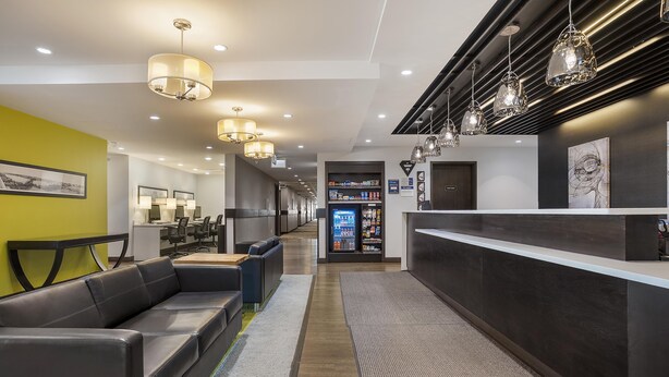Un hall d’hôtel moderne avec des sièges en cuir, un comptoir d’accueil et des luminaires suspendus.
