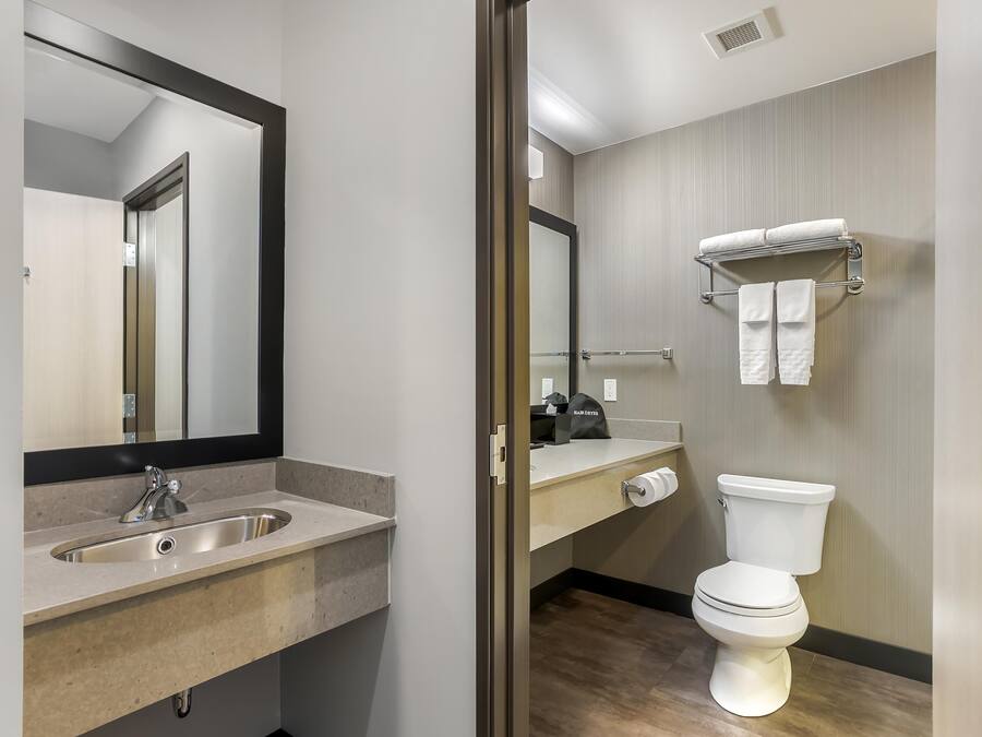 A modern bathroom with a sink, mirror, toilet, and towel rack.