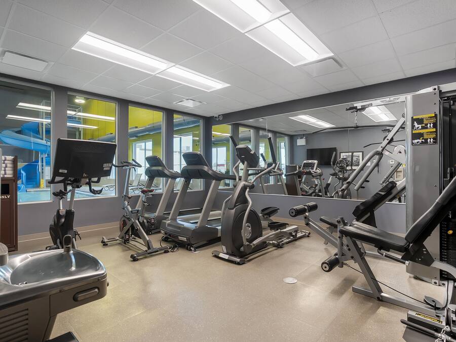 Un gimnasio con cintas de correr, elípticas y equipo de pesas.