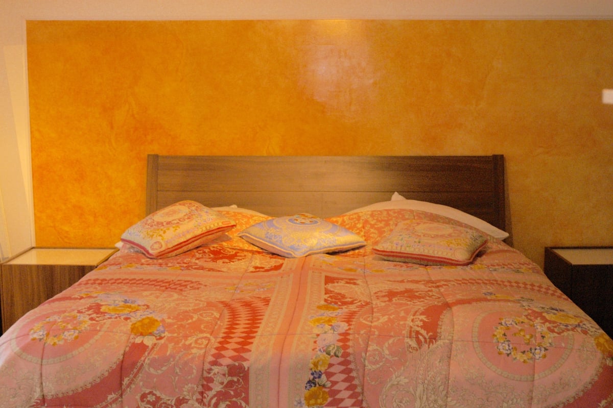 A bed with a patterned bedspread, two pillows, and a wooden headboard.