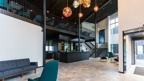 Un hall d’entrée spacieux avec un plafond haut, un escalier et un comptoir d’accueil.