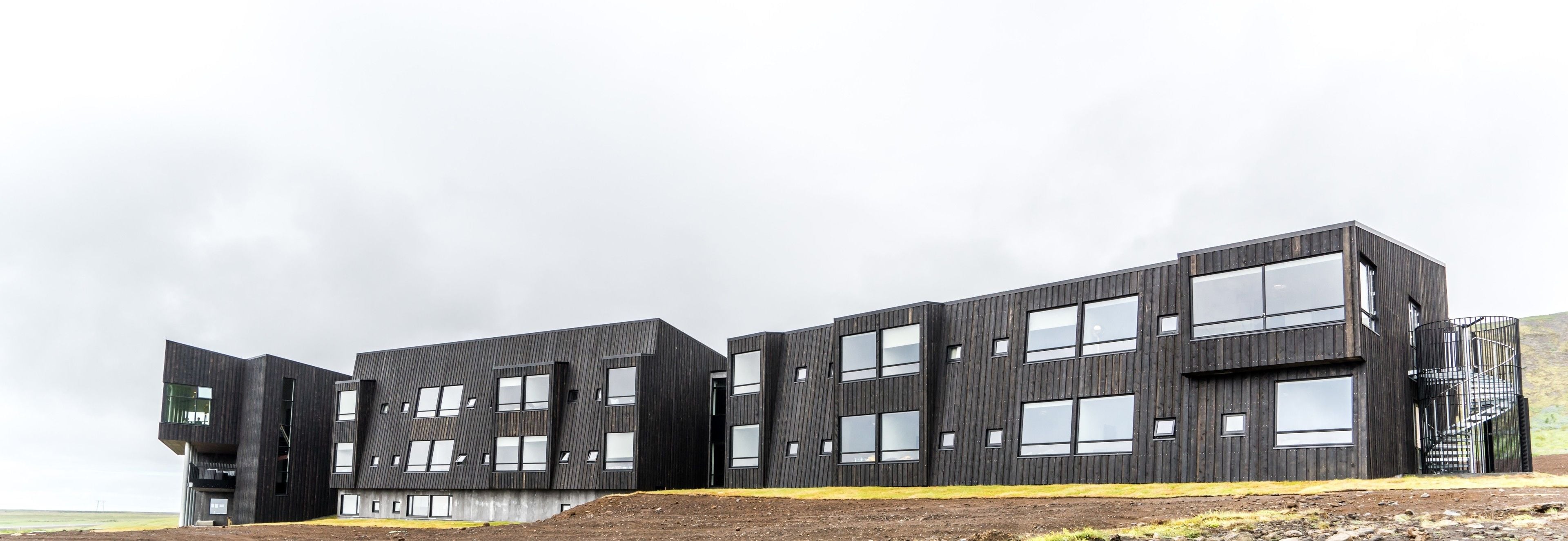 A modern multi-story building with a dark exterior and large windows.