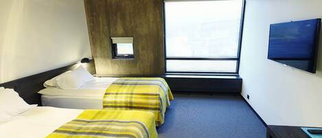A hotel room with two beds, a desk, a TV, and a window providing a view.
