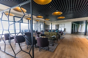 Um espaço de escritório moderno com piso de madeira, sofás de couro e painéis de parede geométricos.