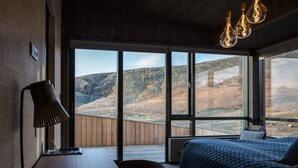 Une chambre avec une grande fenêtre, un lit, un bureau et une chaise.