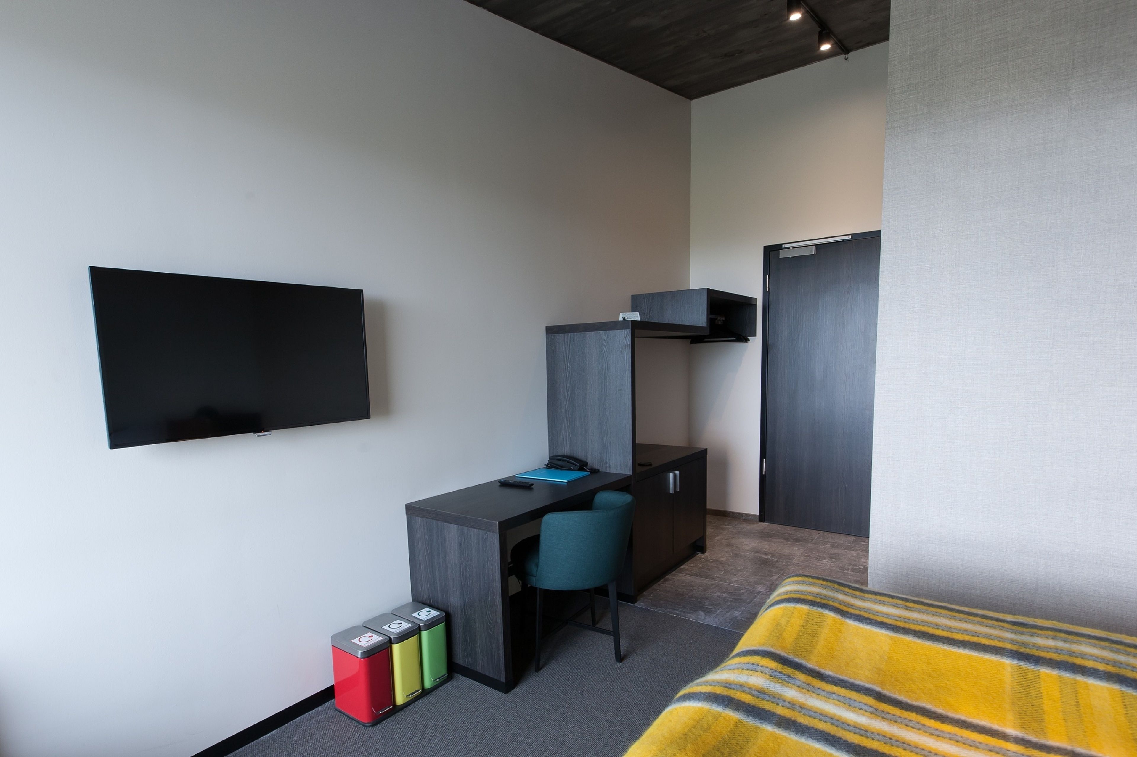 Une chambre moderne équipée d’un bureau, d’une chaise et d’un lit avec une couverture à rayures.
